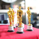 Golden trophies displayed on red tablecloth.