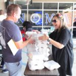 People distributing food containers at an event.