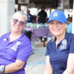 Two women smiling at an outdoor event.