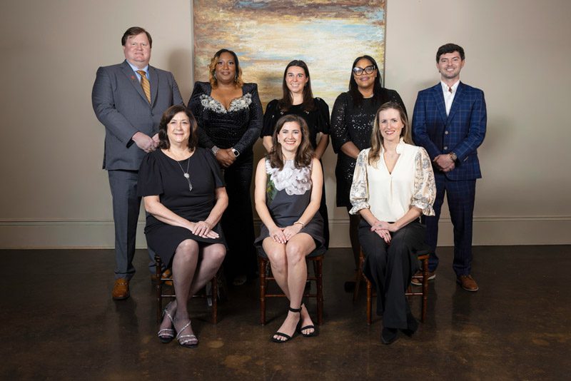 Group of eight people posing together indoors.
