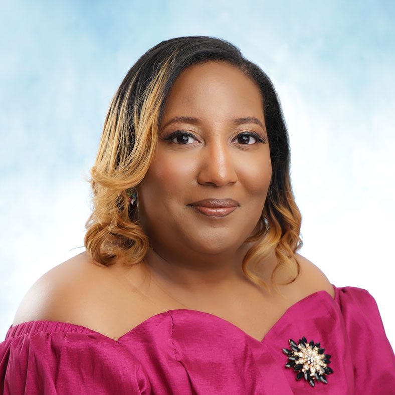Woman in pink dress with floral brooch.