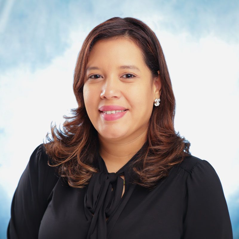 Woman smiling in front of light background.