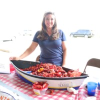Woman with tray of crawfish at table.
