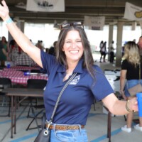 Woman smiling and holding cup at event.