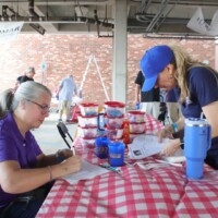 Two women working at a table outdoors.