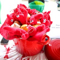 Red pot with toy lobsters and vegetables.