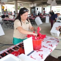 People preparing table at outdoor event.