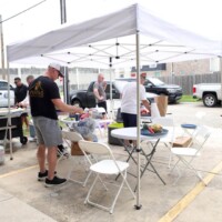 People cooking under a white canopy tent.