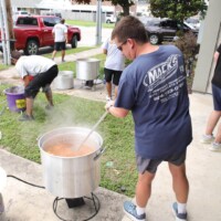 People cooking outdoors in large pots.