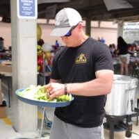 Man preparing food at outdoor event.