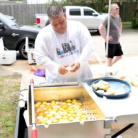 Man preparing food outdoors near vehicles.