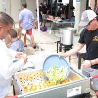 People preparing food at an outdoor event.