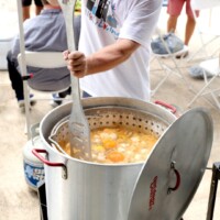 Person stirring large pot of food.