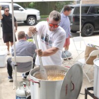 Man cooking in large outdoor pot.