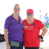 Two women smiling at outdoor event.