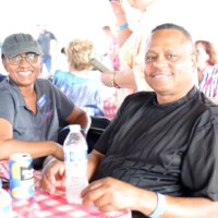 Smiling people sitting at a picnic table.