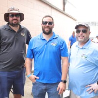 Three men smiling in casual outdoor setting.