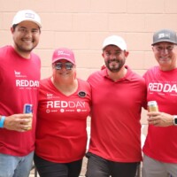 Four people in red shirts smiling together.