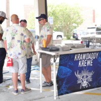 Group gathered near "Krawdaddy Krewe" booth outdoors.