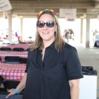 Smiling woman at outdoor event with tables.