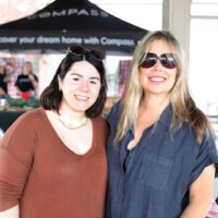 Two women smiling at outdoor event.