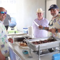 Men preparing barbecue at outdoor event.