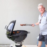 Man grilling meat on a charcoal barbecue.