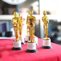 Golden trophies displayed on red tablecloth.