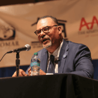 Man speaking at conference with microphone.