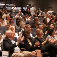 Audience clapping in a crowded theater.