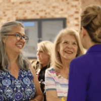 Women talking and smiling at an event.