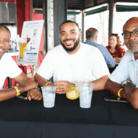 Three men sitting at a table, smiling.
