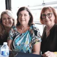 Three women smiling at a table.