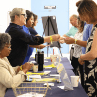 People exchanging documents at a registration table.