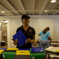 Volunteer smiling behind table of colorful folders